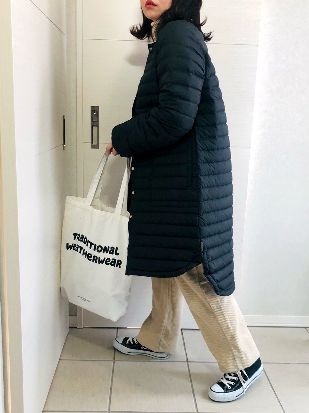 ブラック系のダウンジャケット/コート、ホワイト系のニット/セーター、ベージュ系のその他パンツを着用したレディースの冬コーディネートの3枚目の写真