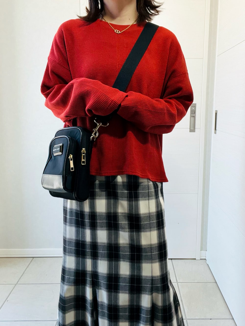ブラック系のスカート、レッド系のTシャツ/カットソー、ブラック系のショルダーバッグを着用したレディースの秋コーディネートの2枚目の写真