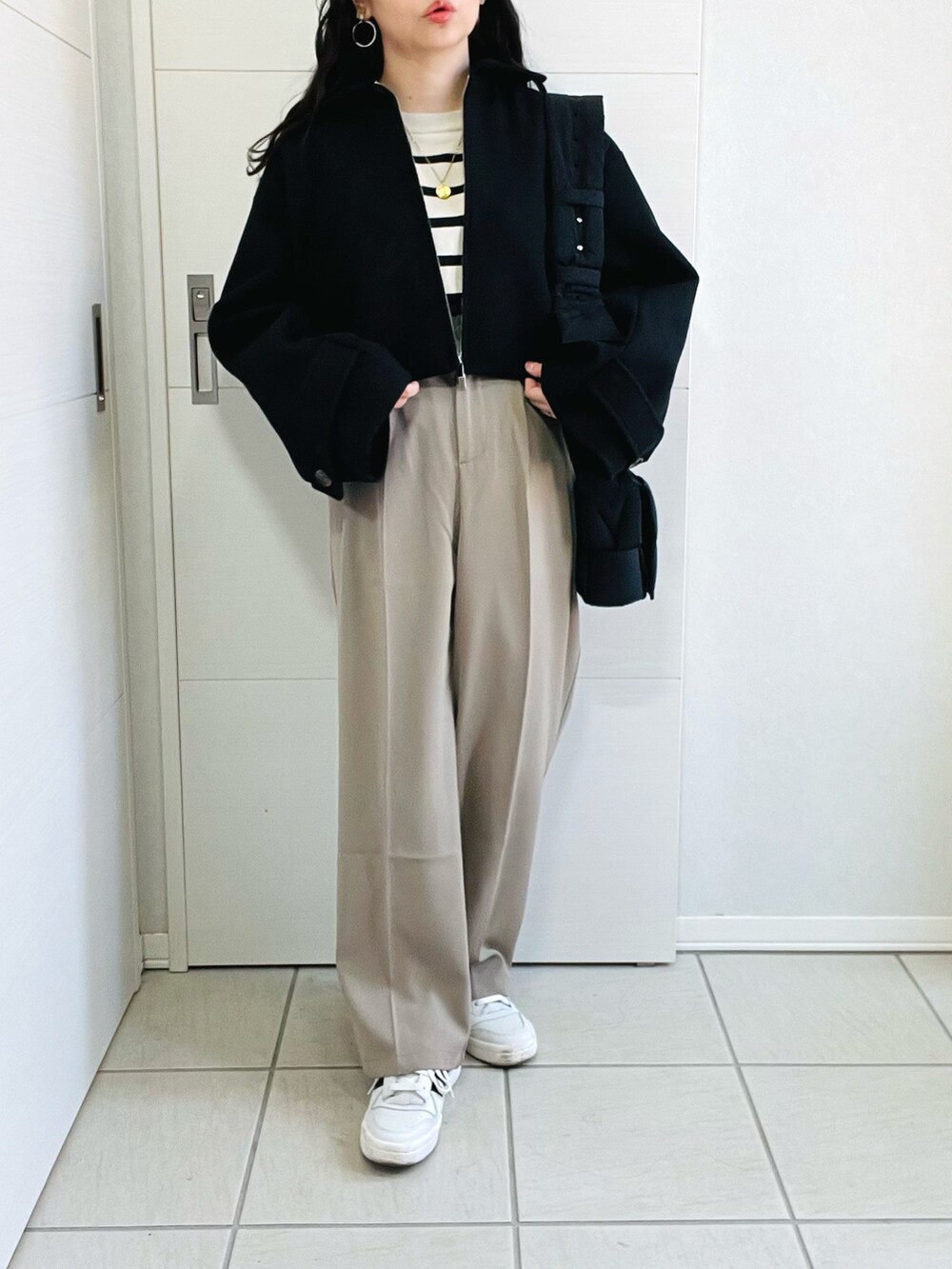 ブラック系のブルゾン、ホワイト系のニット/セーター、ベージュ系のスラックスを着用したレディースの秋コーディネートの2枚目の写真