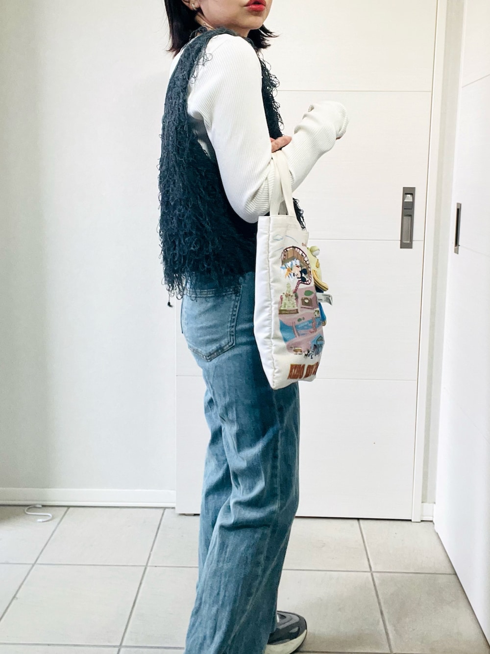 グレー系のベスト、グレー系のスニーカー、ブルー系のデニムパンツを着用したレディースの春コーディネートの4枚目の写真