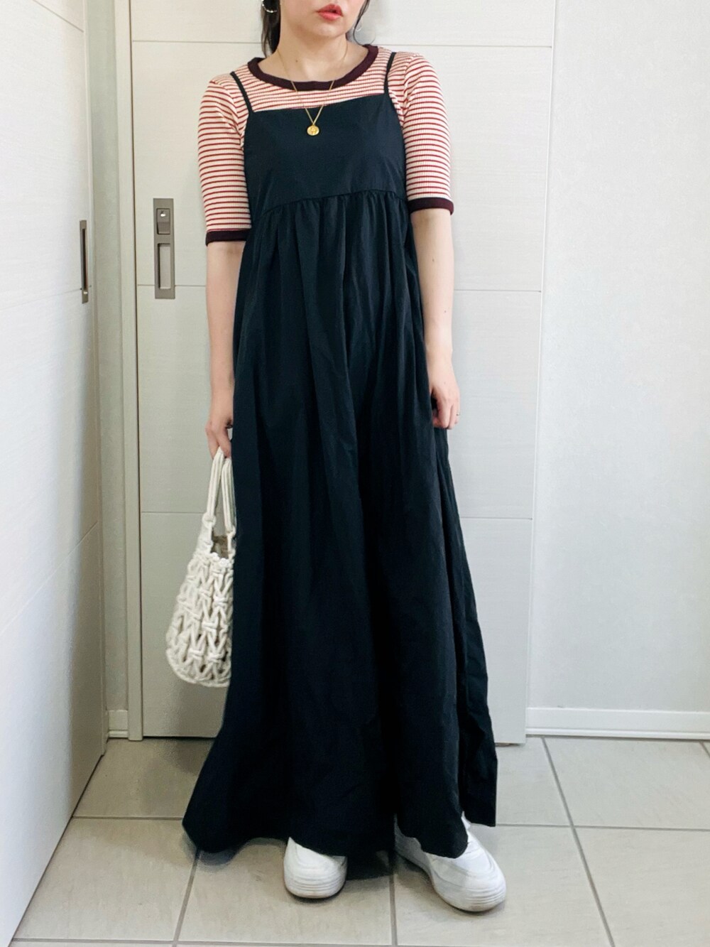 レッド系のTシャツ/カットソー、ブラック系のワンピース、ホワイト系のスニーカーを着用したレディースの夏コーディネートの2枚目の写真