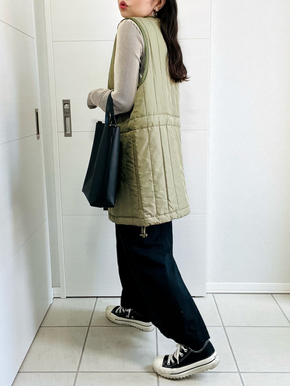 グリーン系のベスト、ベージュ系のTシャツ/カットソー、ブラック系のスカートを着用したレディースの秋コーディネートの5枚目の写真