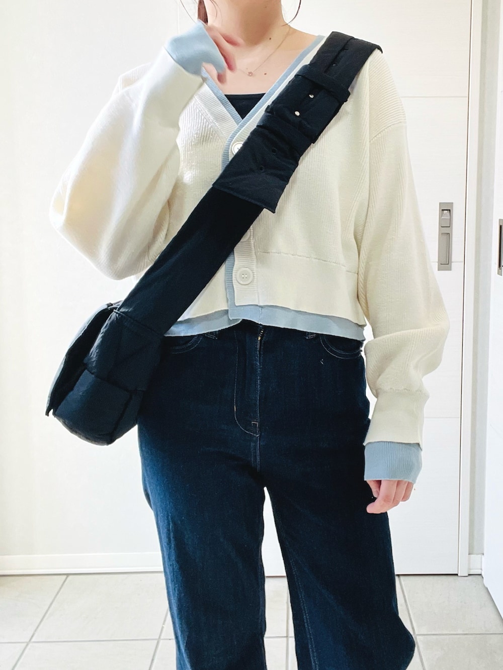 ホワイト系のカーディガン/ボレロ、グレー系のスニーカー、ブルー系のデニムパンツを着用したレディースの春コーディネートの3枚目の写真