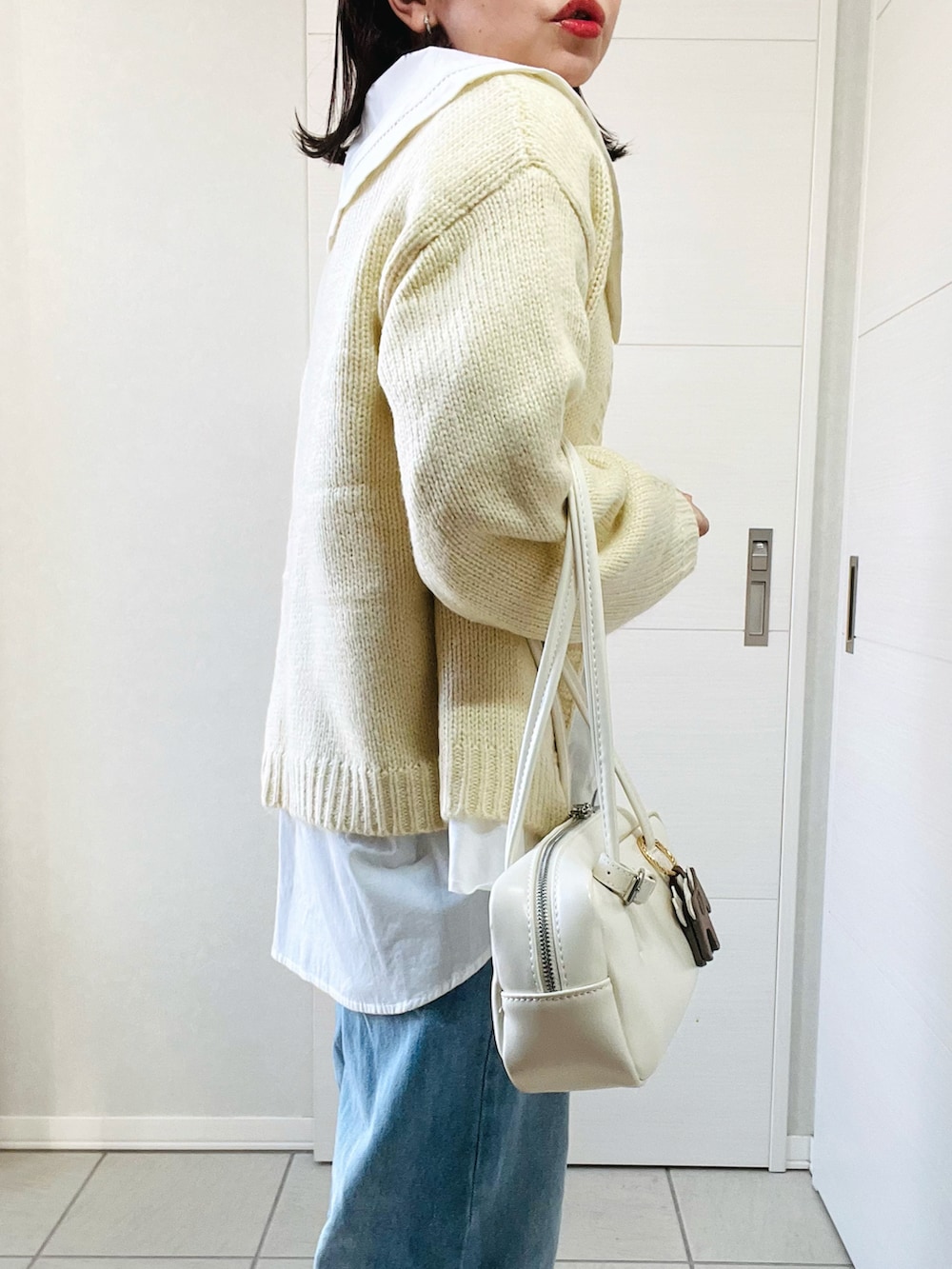 ホワイト系のカーディガン/ボレロ、ホワイト系のシャツ/ブラウス、ブルー系のデニムパンツを着用したレディースの冬コーディネートの3枚目の写真