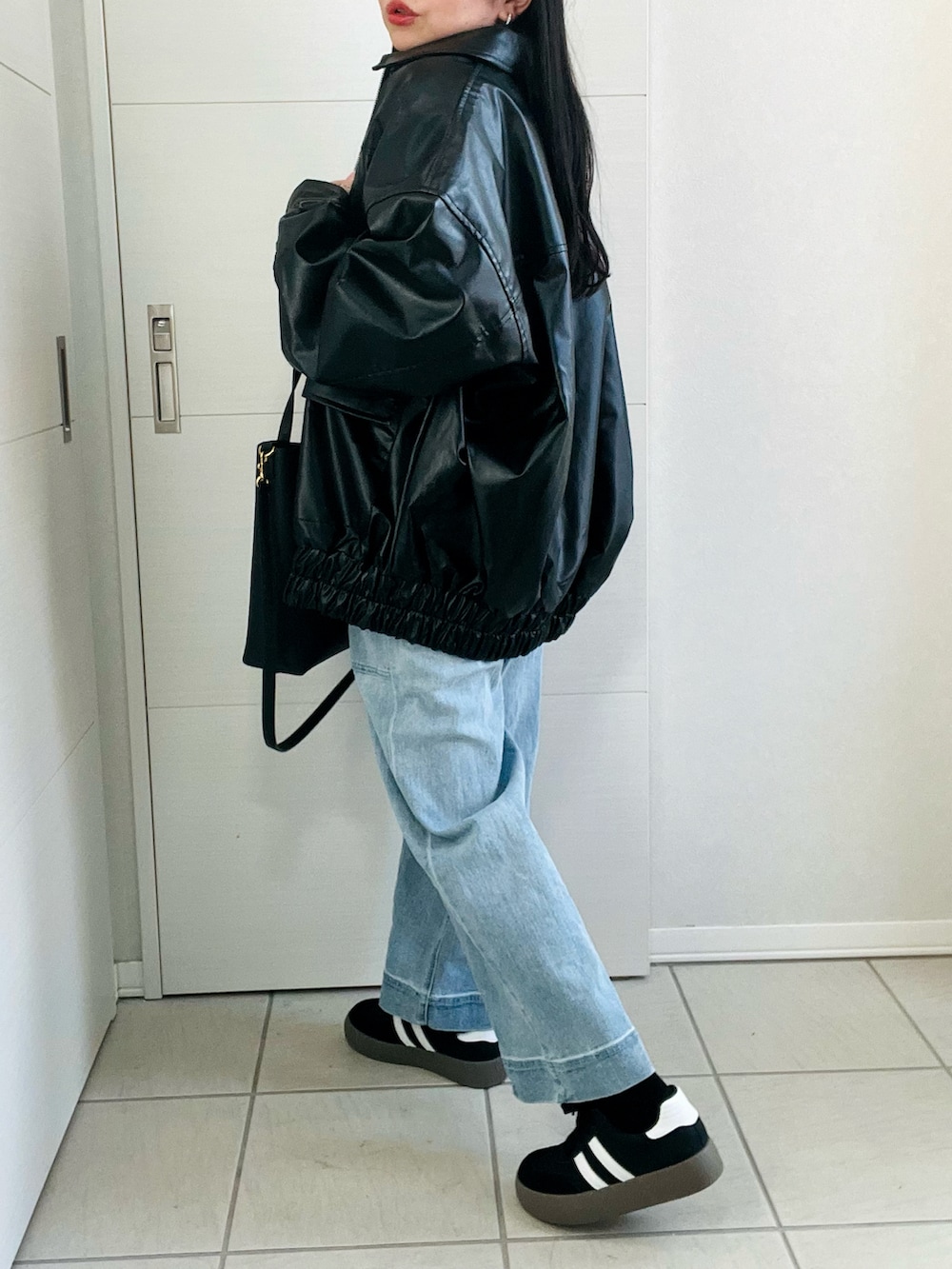 ブラック系のブルゾン、ホワイト系のTシャツ/カットソー、ブルー系のデニムパンツを着用したレディースの冬コーディネートの5枚目の写真