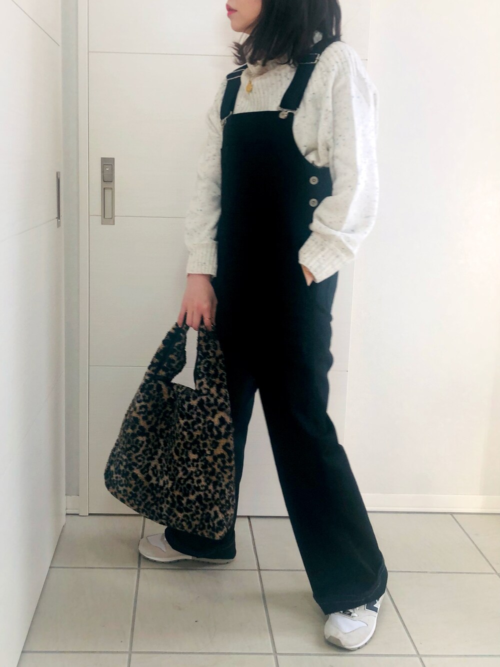 ベージュ系のノーカラーコート、ブラック系のサロペット/オーバーオール、ホワイト系のニット/セーターを着用したレディースの冬コーディネートの3枚目の写真