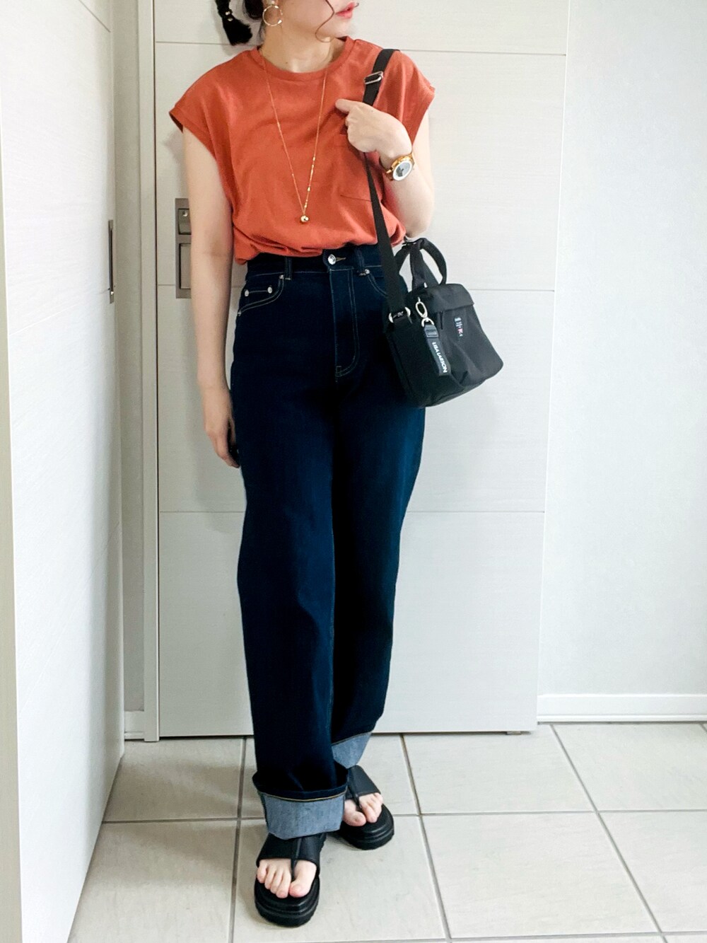 オレンジ系のTシャツ/カットソー、ブルー系のデニムパンツ、ブラック系のサンダルを着用したレディースの夏コーディネートの3枚目の写真