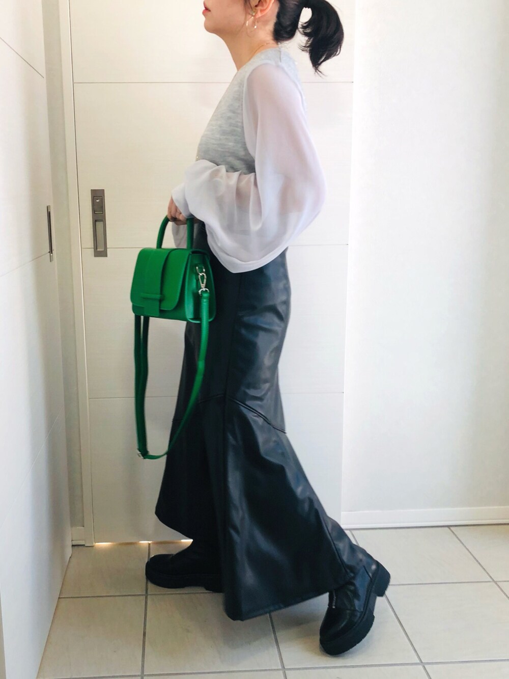 グレー系のTシャツ/カットソー、ブラック系のスカート、ブラック系のブーツを着用したレディースの冬コーディネートの4枚目の写真