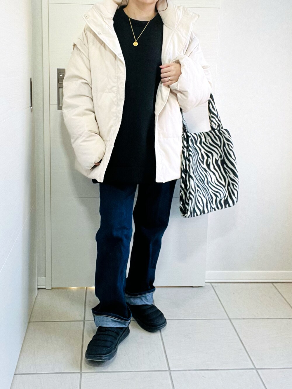 ブラック系のスウェット、ホワイト系のダウンジャケット/コート、ブルー系のデニムパンツを着用したレディースの冬コーディネートの4枚目の写真