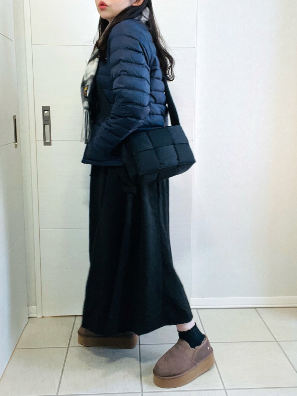 ブルー系のダウンジャケット/コート、ブラック系のワンピース、ベージュ系のスリッポンを着用したレディースの冬コーディネートの5枚目の写真