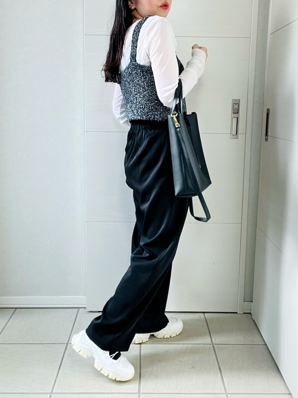 ブラック系のベスト、ホワイト系のTシャツ/カットソー、ブラック系のスラックスを着用したレディースの秋コーディネートの5枚目の写真