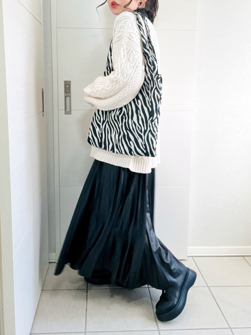 ホワイト系のニット/セーター、ブラック系のTシャツ/カットソー、ブラック系のスカートを着用したレディースの秋コーディネートの4枚目の写真
