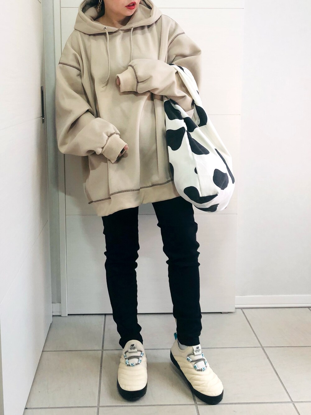 ベージュ系のパーカー、ブラック系のデニムパンツ、ホワイト系のスリッポンを着用したレディースの秋コーディネートの2枚目の写真