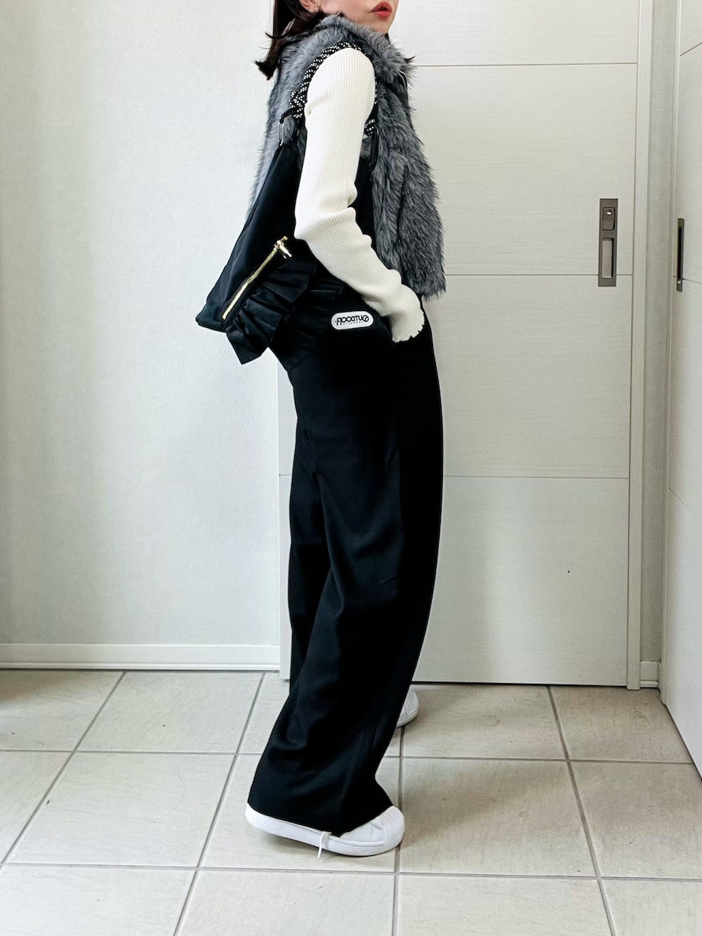 ホワイト系のニット/セーター、グレー系のベスト、ブラック系のスラックスを着用したレディースの秋コーディネートの4枚目の写真