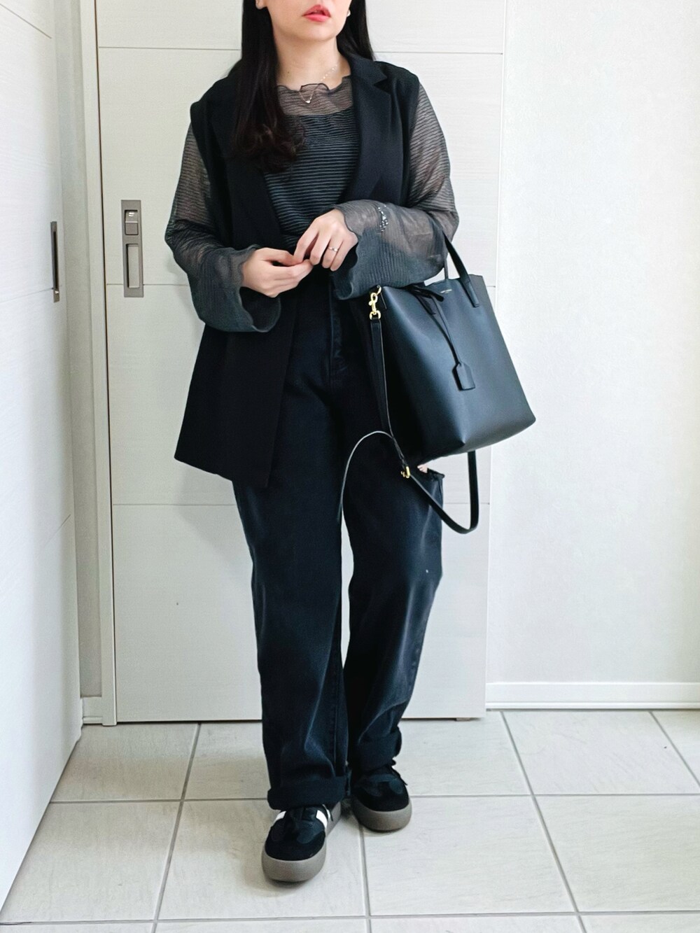 グレー系のTシャツ/カットソー、ブラック系のベスト、ブラック系のデニムパンツを着用したレディースの春コーディネートの4枚目の写真