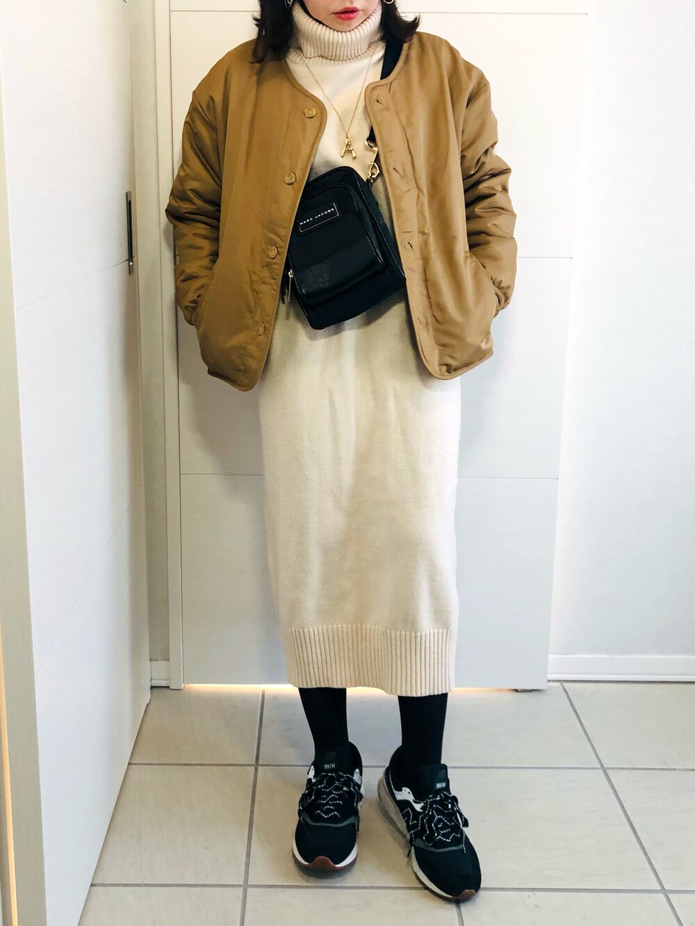 ベージュ系のブルゾン、ホワイト系のワンピース、ブラック系のスニーカーを着用したレディースの冬コーディネートの2枚目の写真