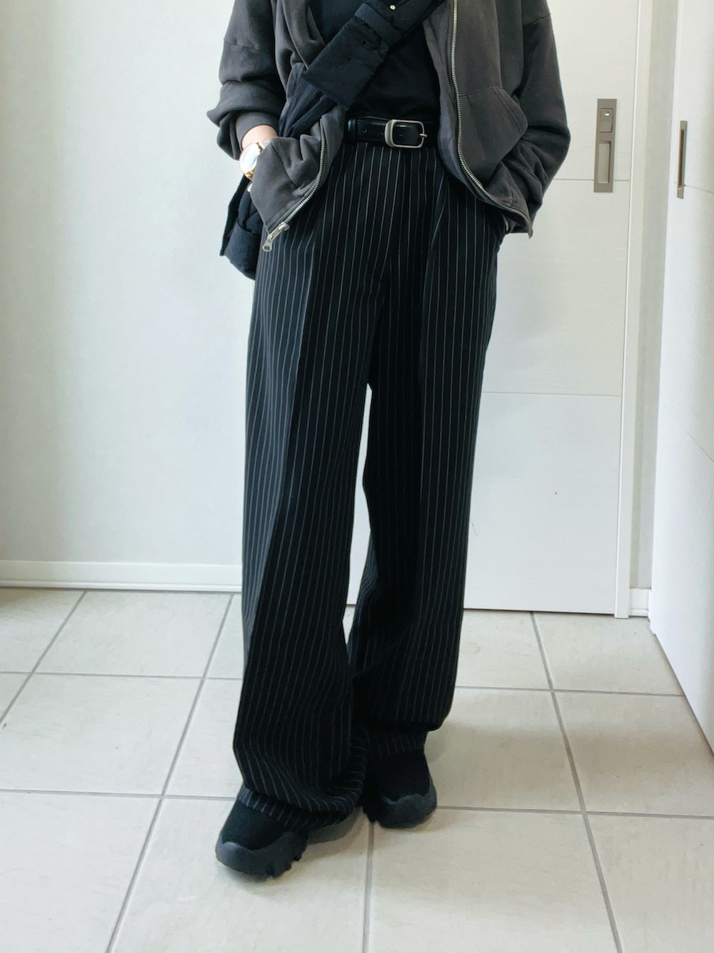 ブラック系のデニムパンツ、グレー系のパーカー、ブラック系のブーツを着用したレディースの秋コーディネートの2枚目の写真