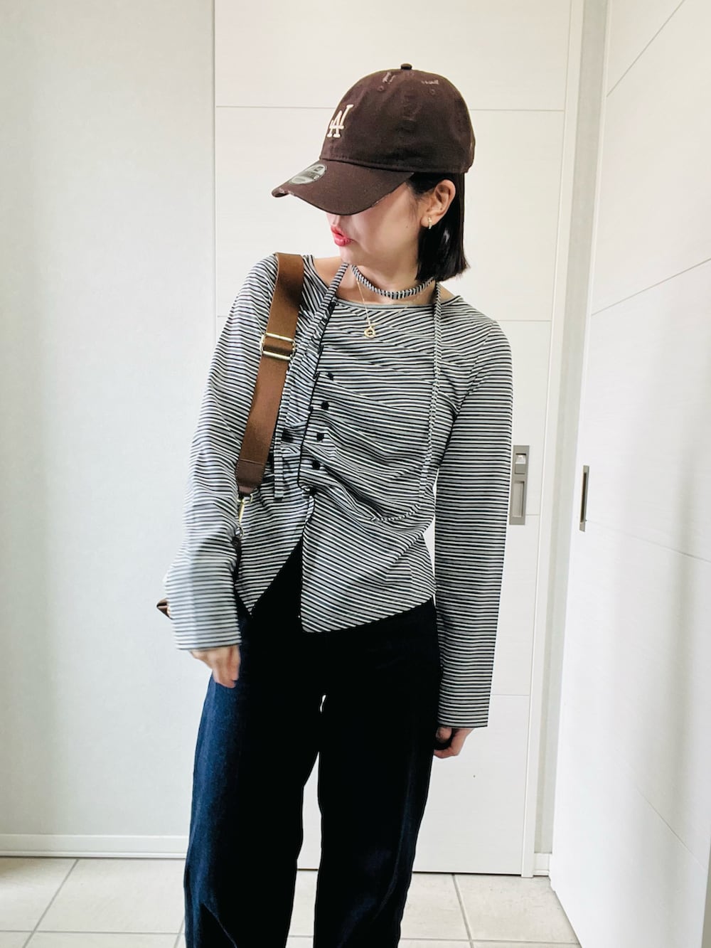 ブラック系のTシャツ/カットソー、ブラウン系のスニーカー、ブルー系のデニムパンツを着用したレディースの秋コーディネートの2枚目の写真