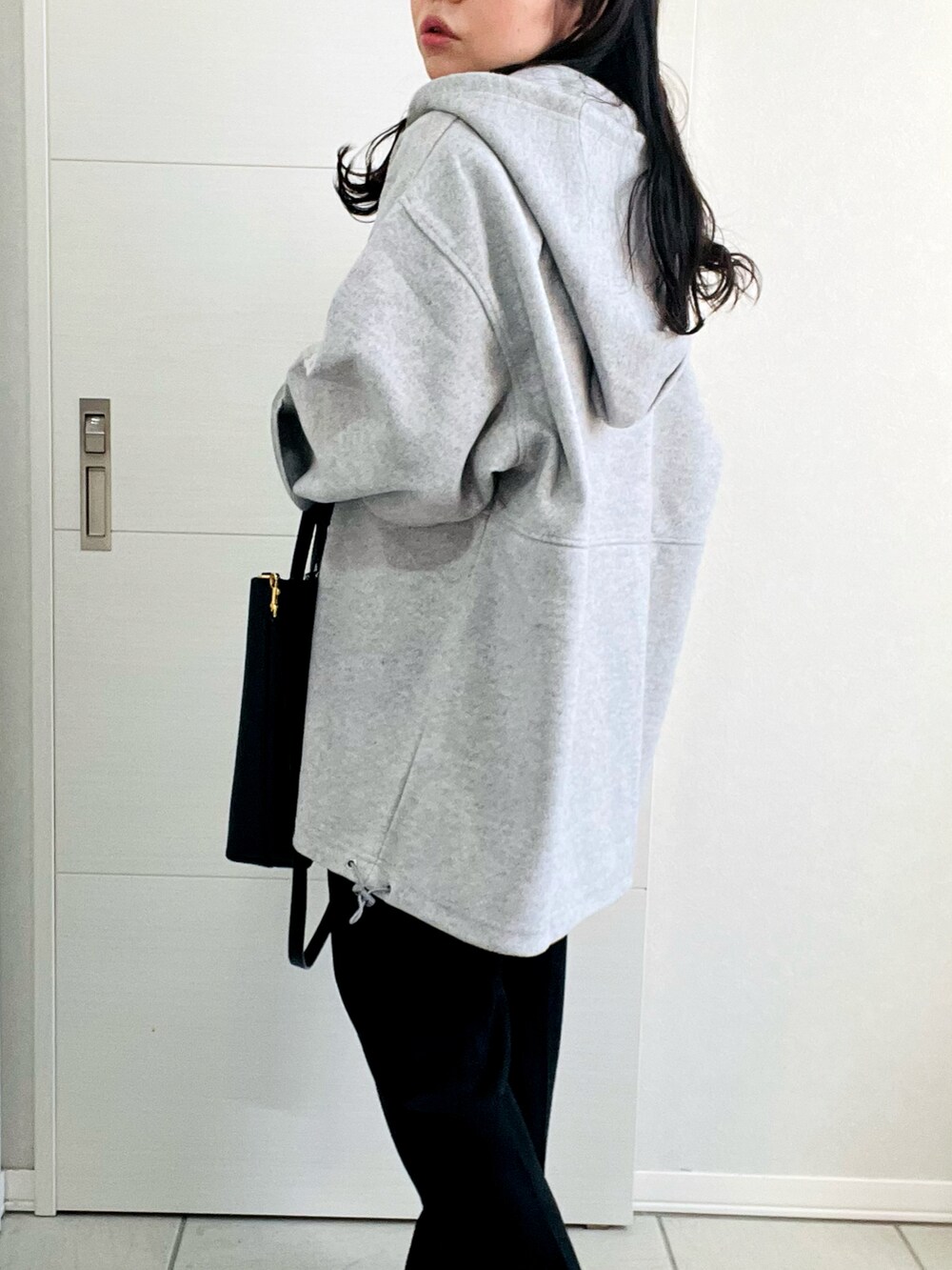 グレー系のパーカー、グレー系のTシャツ/カットソー、ブラック系のスラックスを着用したレディースの冬コーディネートの3枚目の写真