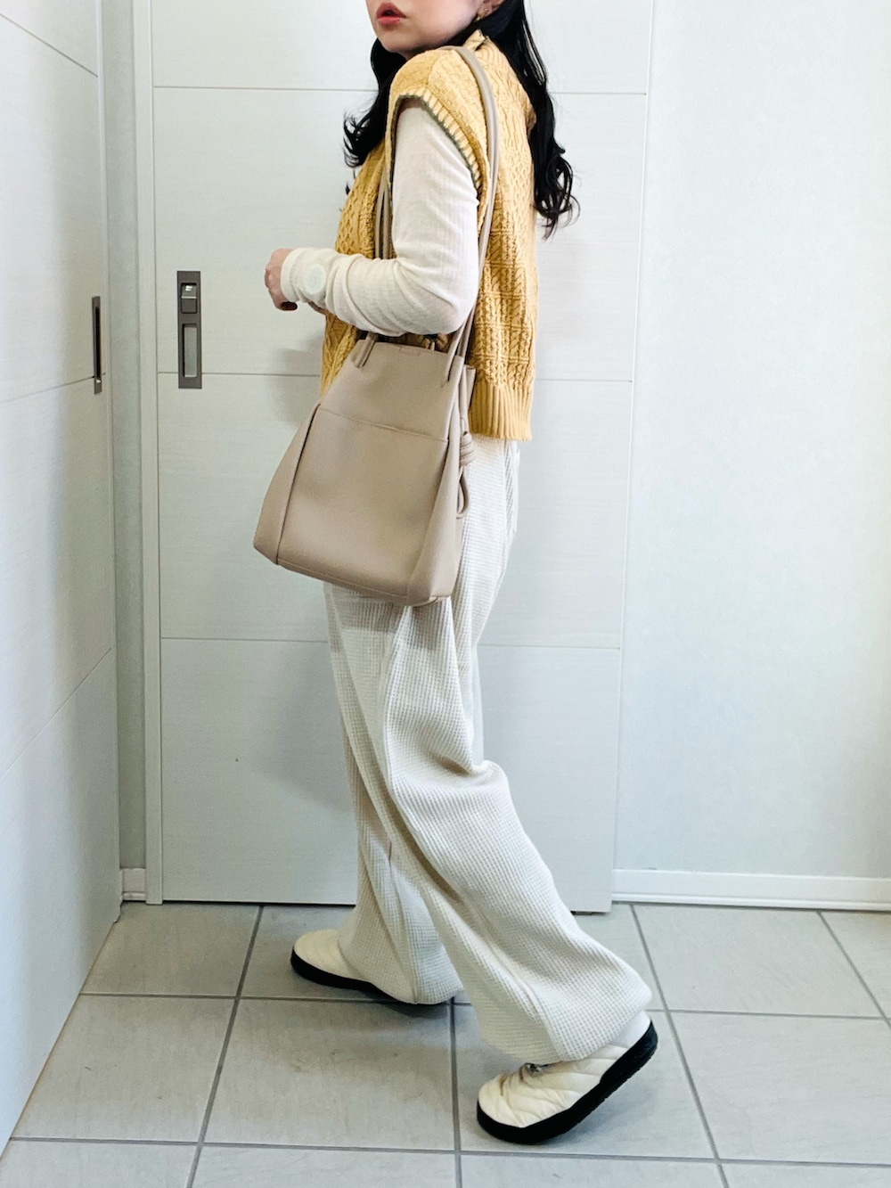 イエロー系のベスト、ホワイト系のTシャツ/カットソー、ベージュ系のその他パンツを着用したレディースの秋コーディネートの4枚目の写真