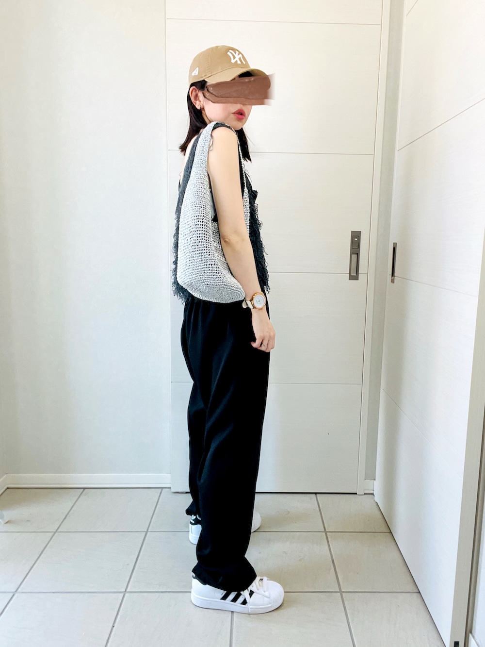 ホワイト系のキャミソール、グレー系のベスト、ブラック系のスラックスを着用したレディースの夏コーディネートの5枚目の写真