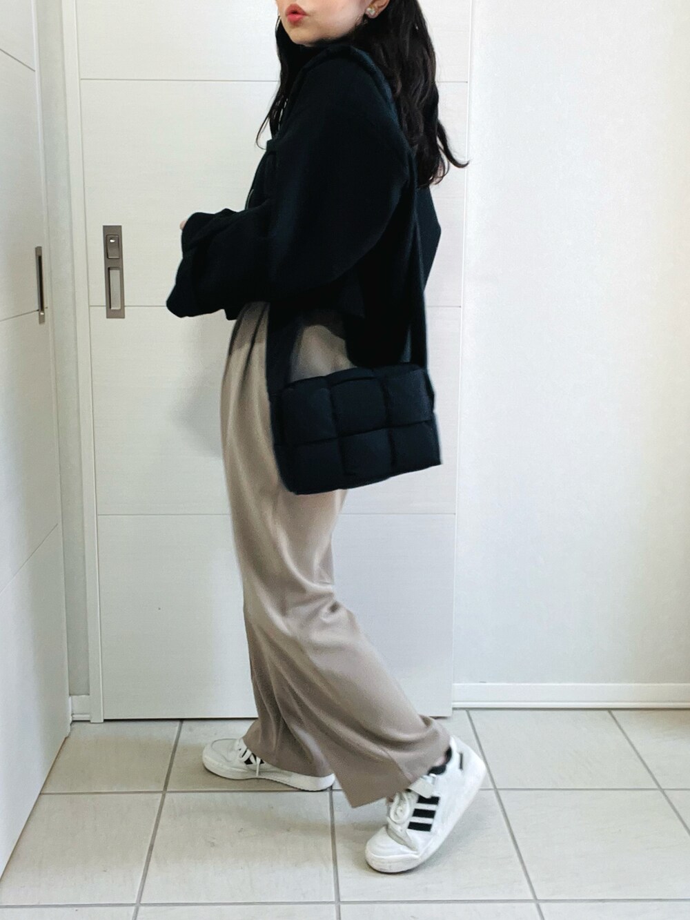 ブラック系のブルゾン、ホワイト系のニット/セーター、ベージュ系のスラックスを着用したレディースの秋コーディネートの5枚目の写真