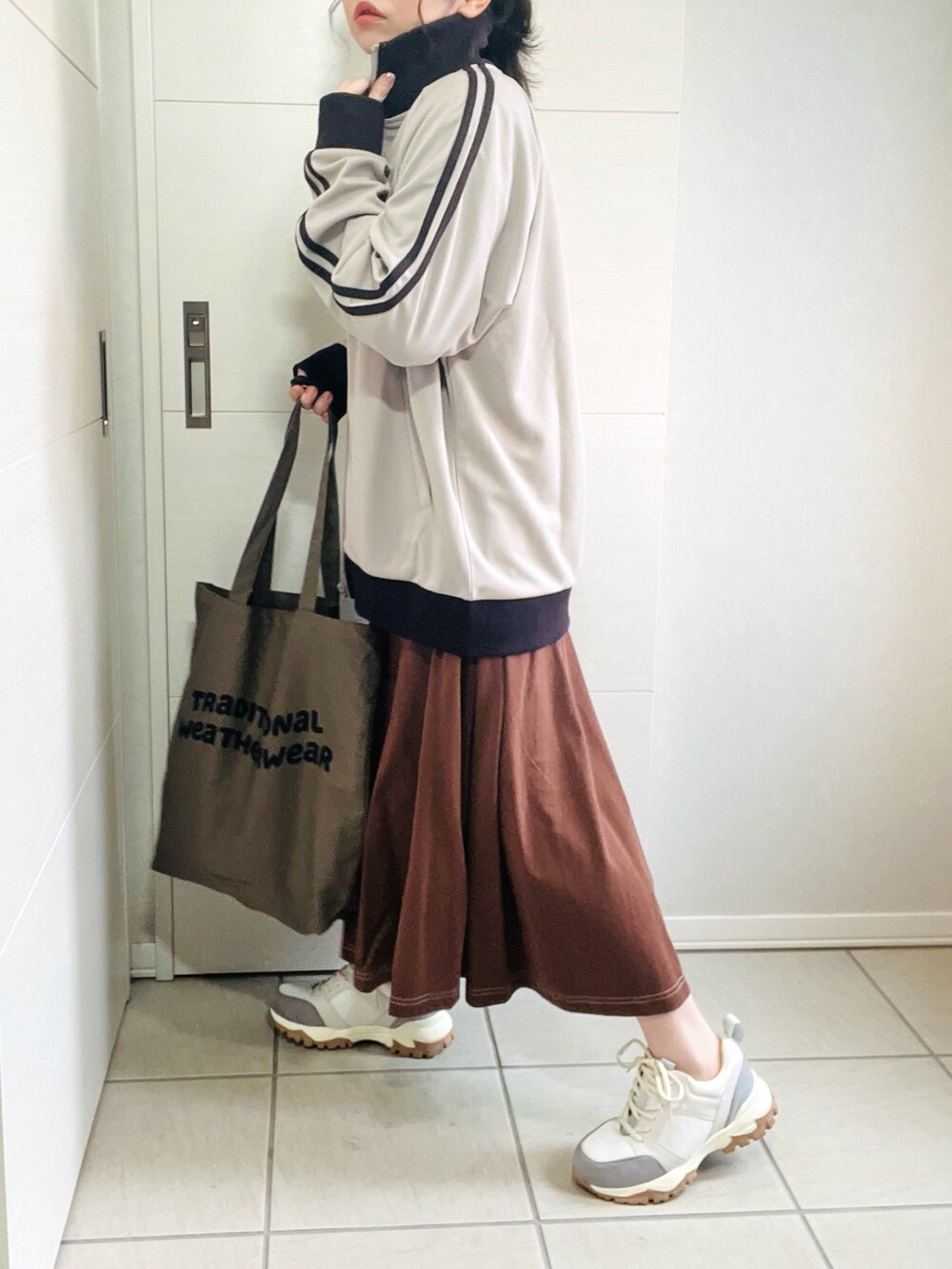 ベージュ系のジャージ、ブラウン系のワンピース、ベージュ系のスニーカーを着用したレディースの秋コーディネートの5枚目の写真