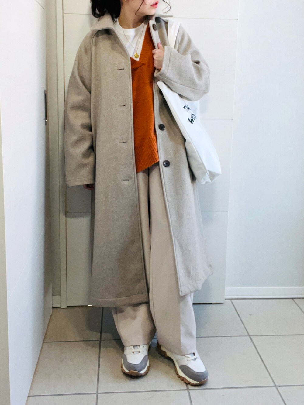 オレンジ系のニット/セーター、ホワイト系のスラックス、ベージュ系のスニーカーを着用したレディースの冬コーディネートの5枚目の写真