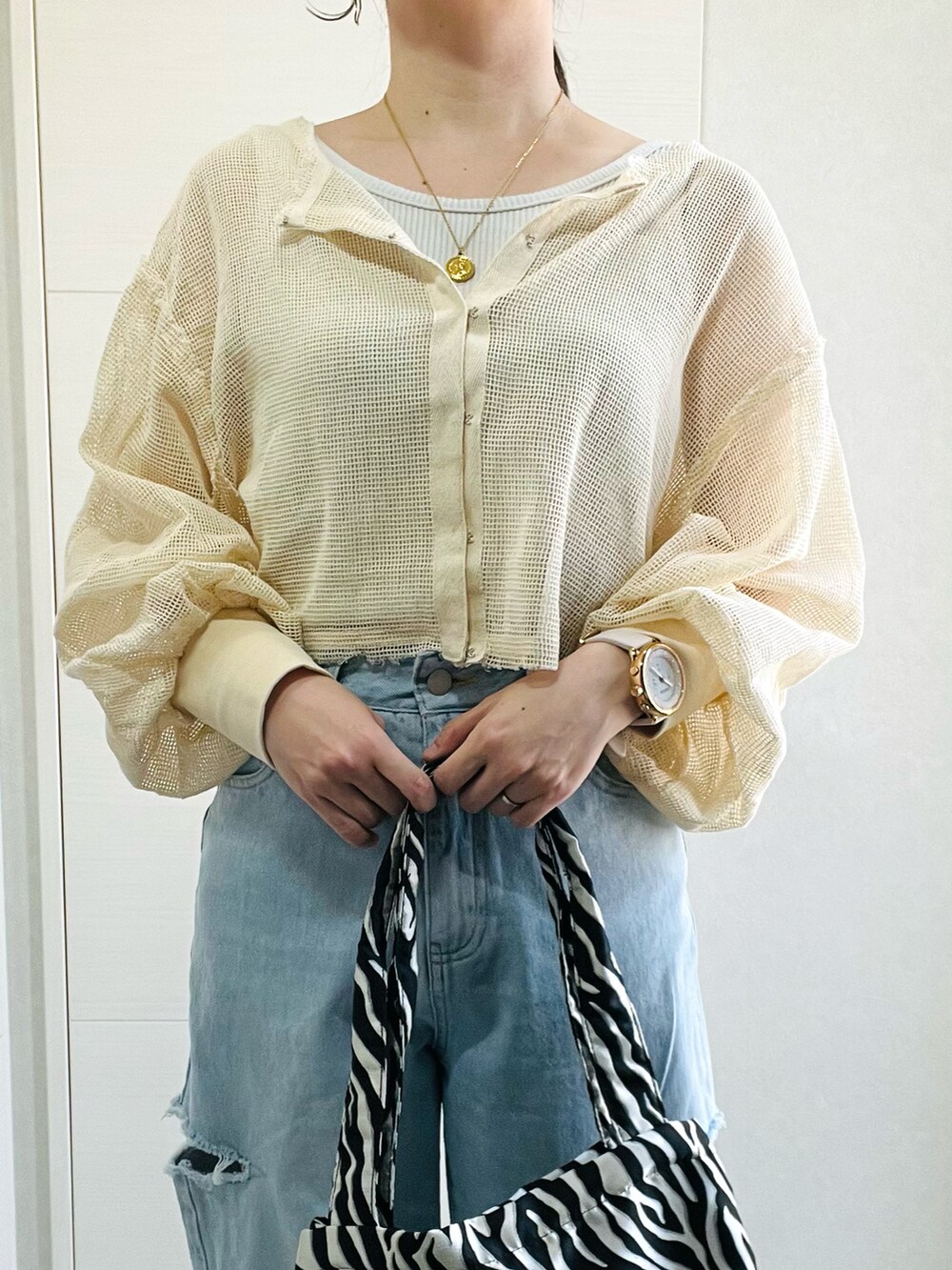 ホワイト系のカーディガン/ボレロ、ブルー系のデニムパンツ、ブラック系のサンダルを着用したレディースの春コーディネートの2枚目の写真