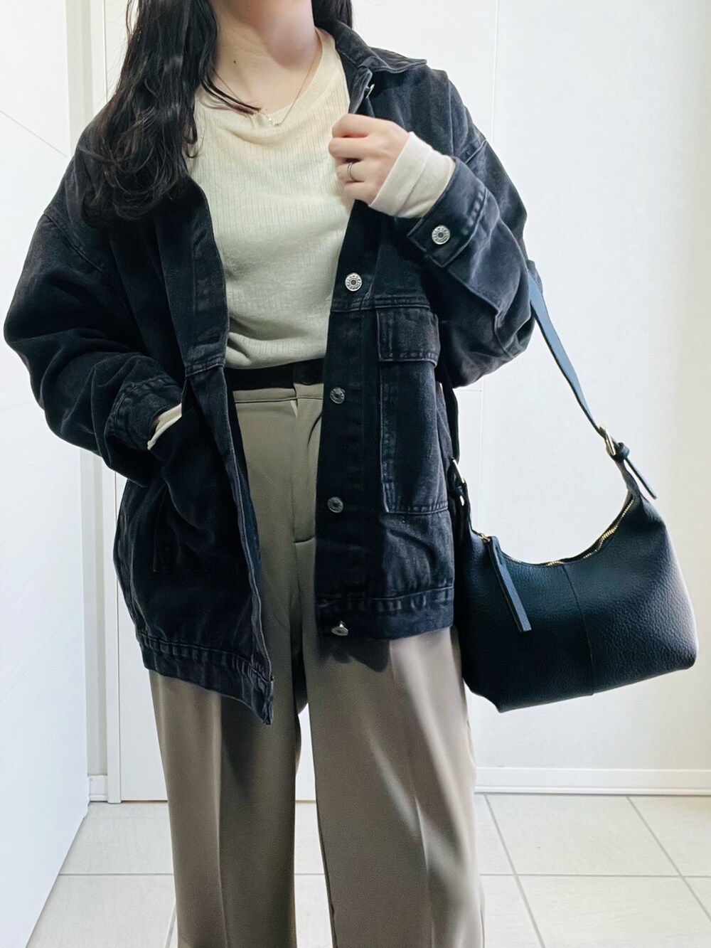 ブラック系のデニムジャケット、ブラック系のスニーカー、ブラック系のショルダーバッグを着用したレディースの冬コーディネートの3枚目の写真