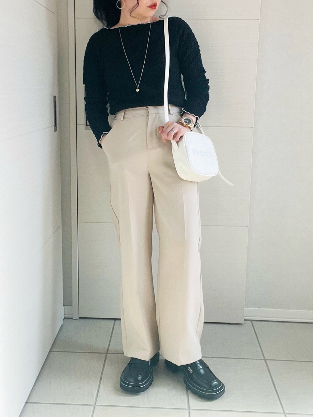 ブラック系のTシャツ/カットソー、ホワイト系のスラックス、ブラック系のローファーを着用したレディースの春コーディネートの2枚目の写真