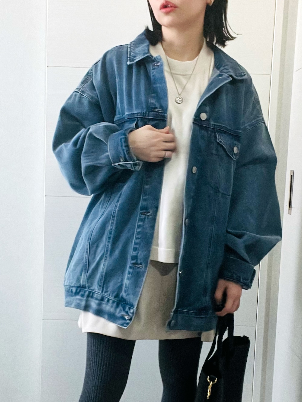 ブルー系のデニムジャケット、ベージュ系のニット/セーター、ホワイト系のスカートを着用したレディースの冬コーディネートの2枚目の写真