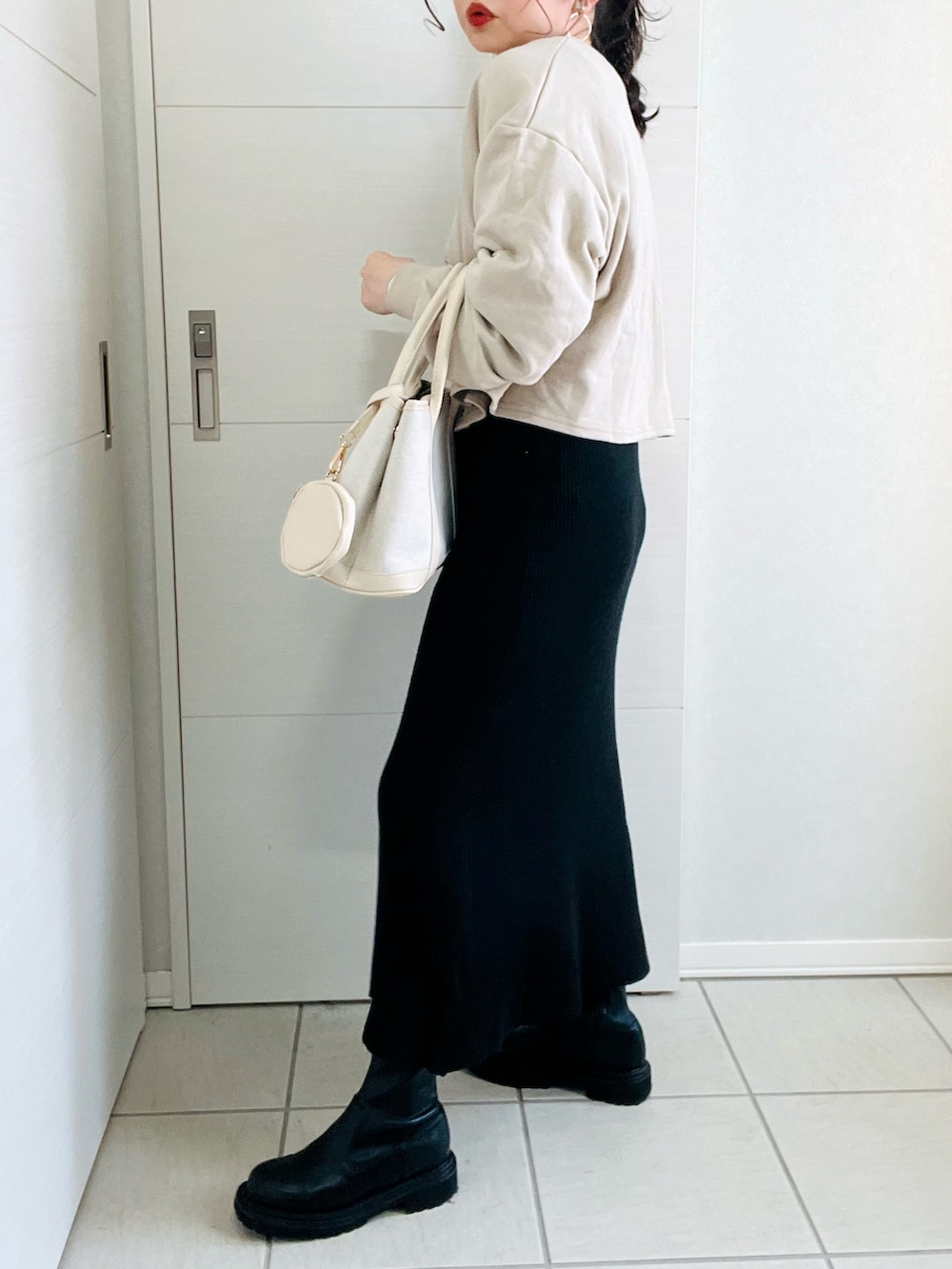 ベージュ系のカーディガン/ボレロ、ブラック系のワンピース、ブラック系のブーツを着用したレディースの冬コーディネートの5枚目の写真