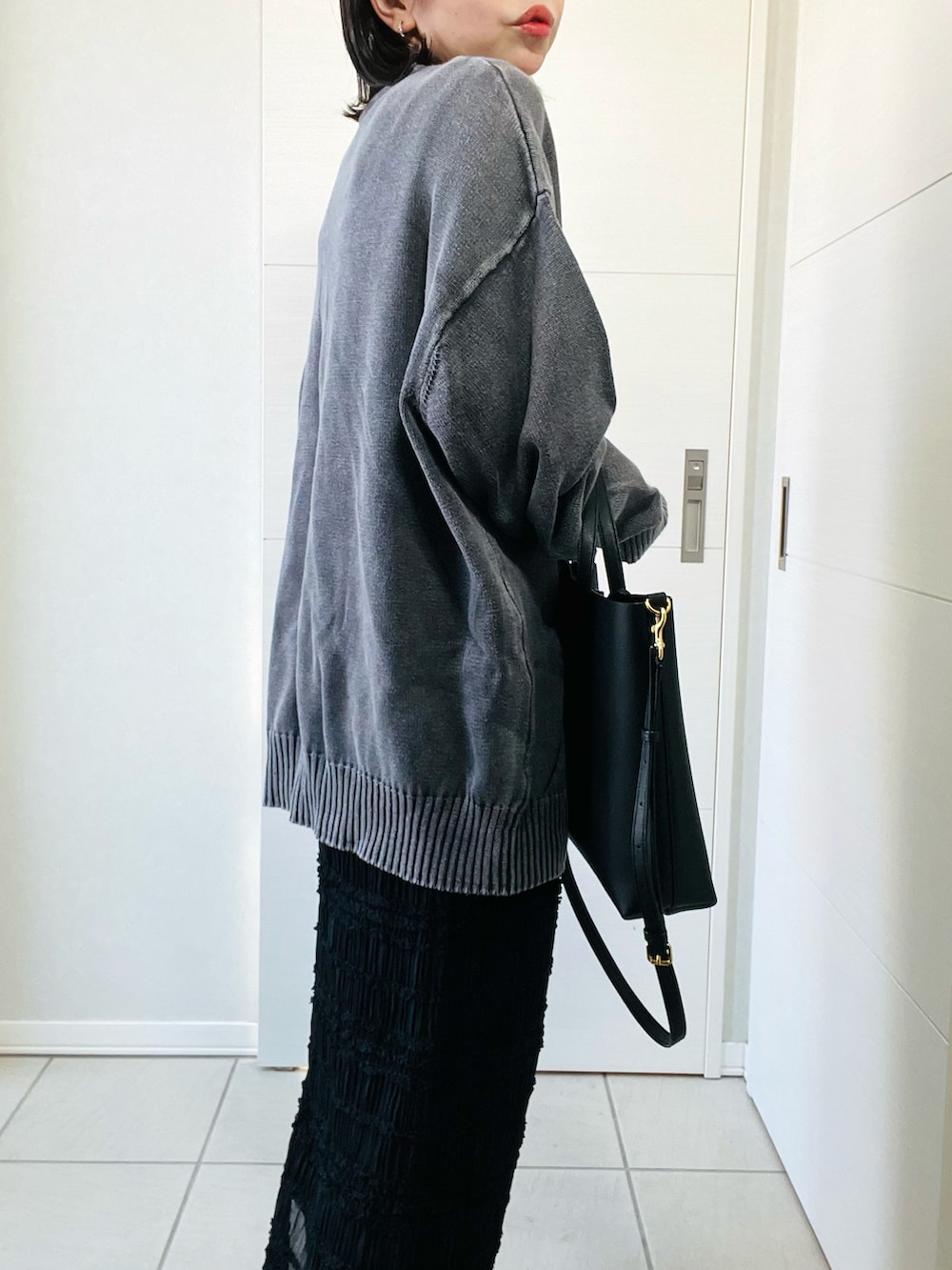 ブラック系のニット/セーター、ブラック系のスカート、ブラック系のブーツを着用したレディースの冬コーディネートの3枚目の写真