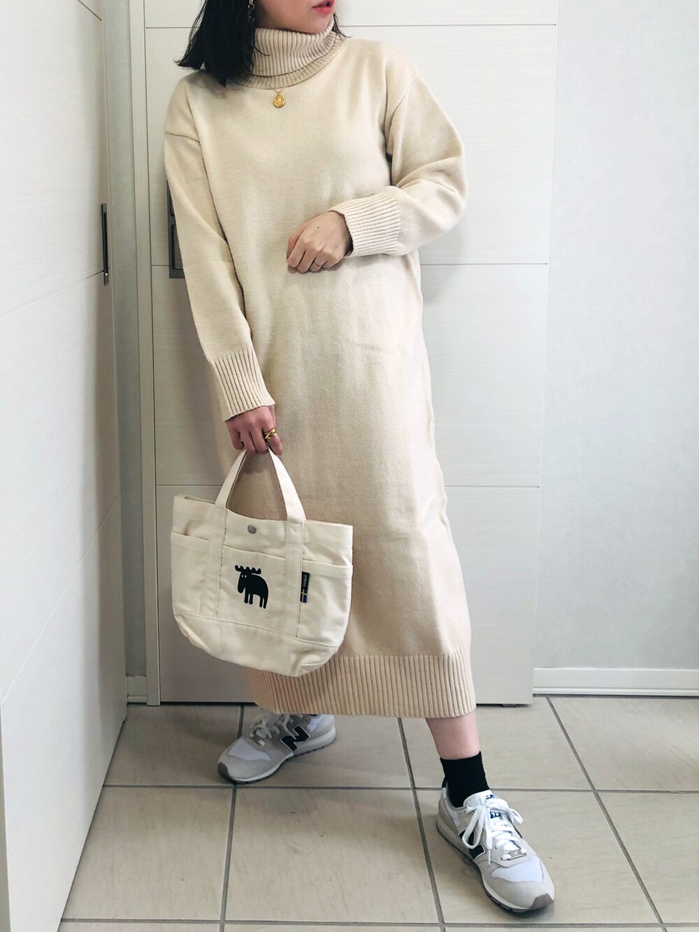 ブラウン系のノーカラーコート、ホワイト系のワンピース、ホワイト系のスニーカーを着用したレディースの秋コーディネートの2枚目の写真