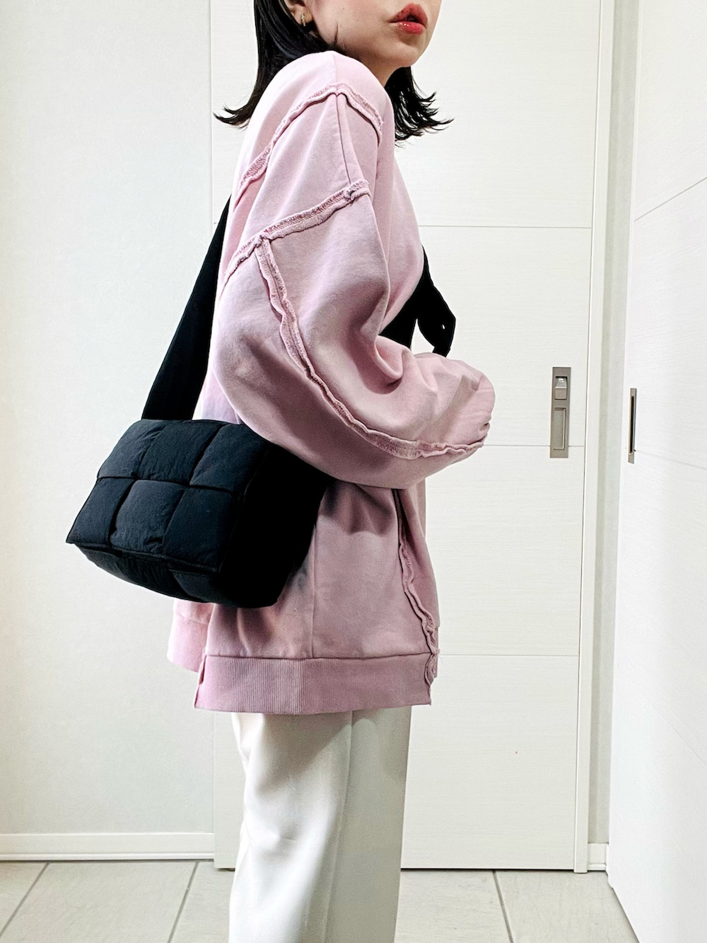 ピンク系のスウェット、ホワイト系のスラックス、ブラック系のスニーカーを着用したレディースの冬コーディネートの3枚目の写真