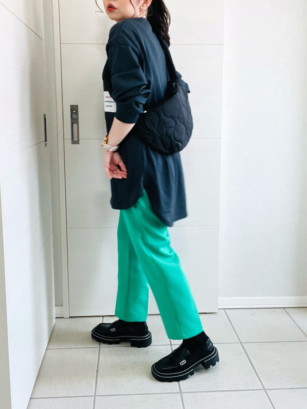 ブラック系のTシャツ/カットソー、グリーン系のスラックス、ブラック系のローファーを着用したレディースの春コーディネートの4枚目の写真