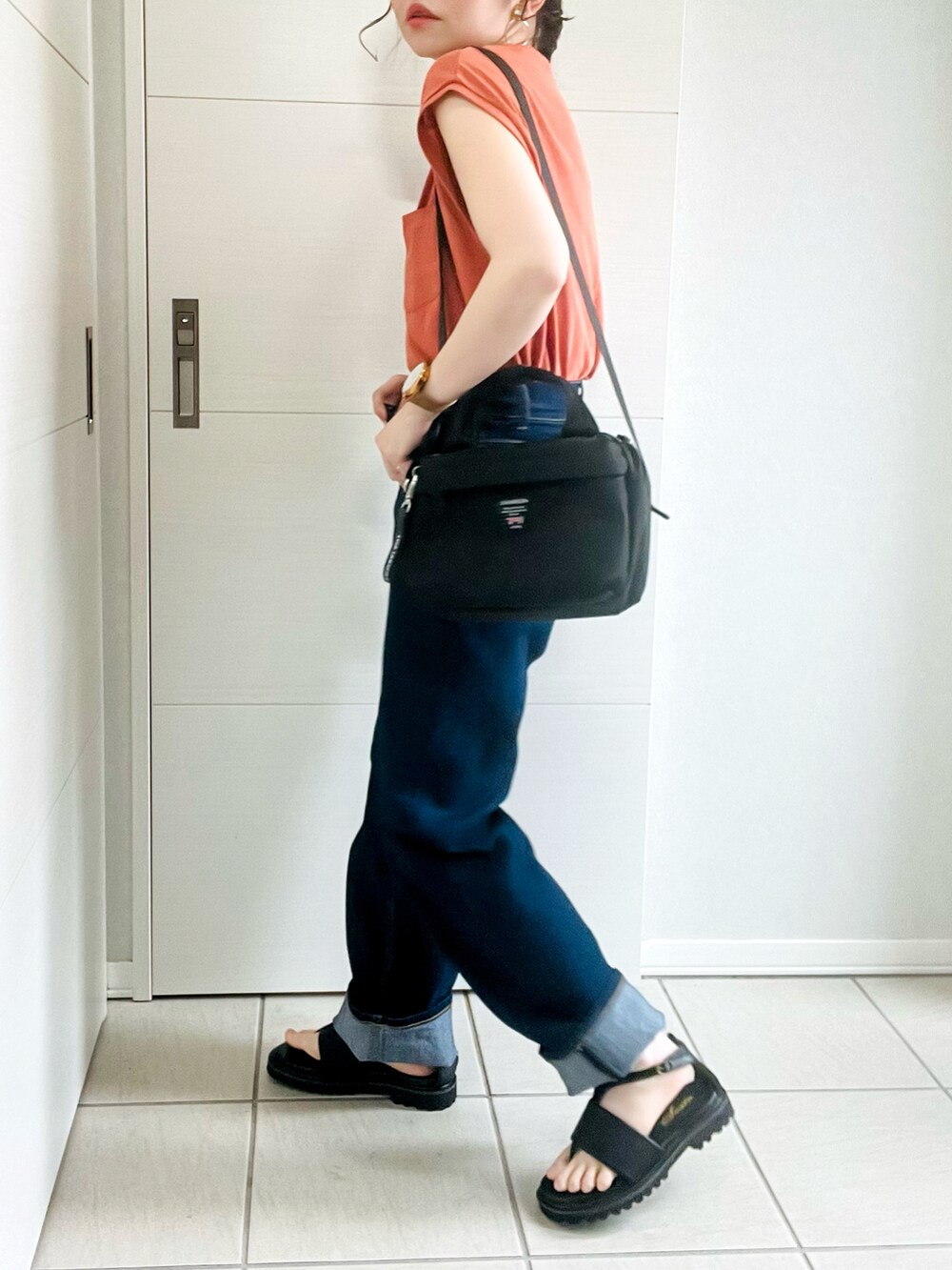 オレンジ系のTシャツ/カットソー、ブルー系のデニムパンツ、ブラック系のサンダルを着用したレディースの夏コーディネートの4枚目の写真