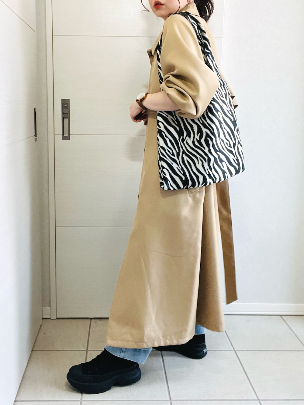 ベージュ系のトレンチコート、ブラック系のキャミソール、ブルー系のデニムパンツを着用したレディースの春コーディネートの5枚目の写真