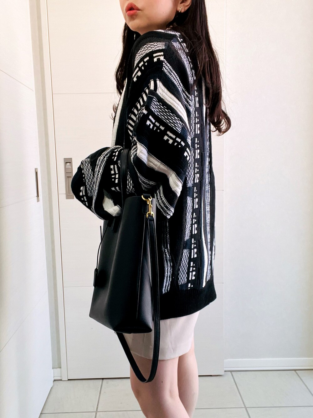 ブラック系のカーディガン/ボレロ、ホワイト系のスラックス、ブラック系のローファーを着用したレディースの春コーディネートの4枚目の写真