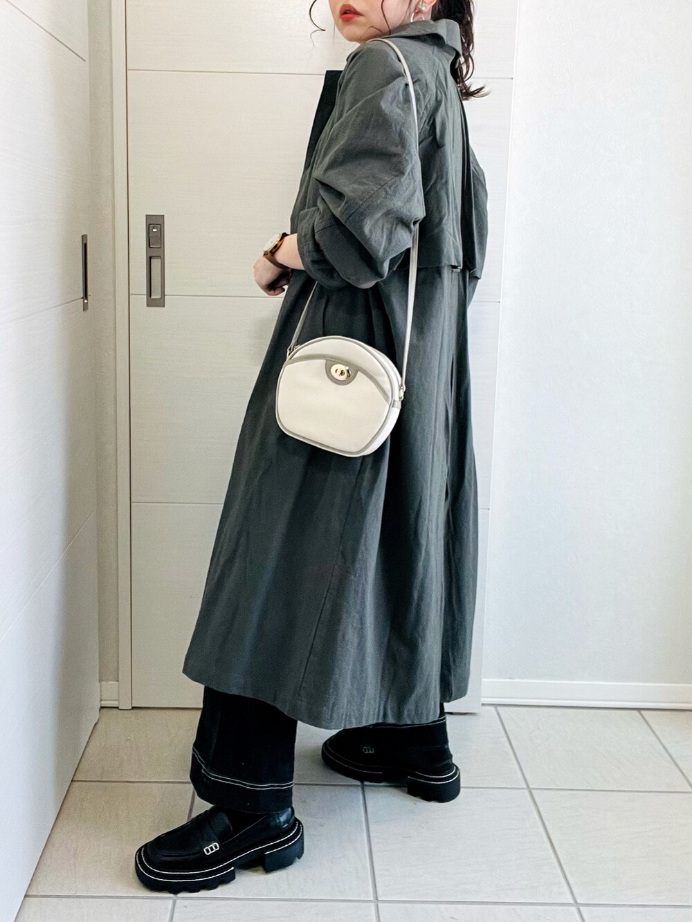 グリーン系のステンカラーコート、ホワイト系のTシャツ/カットソー、ブラック系のデニムパンツを着用したレディースの春コーディネートの5枚目の写真