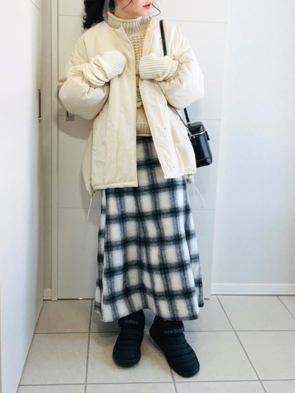 ホワイト系のブルゾン、ホワイト系のニット/セーター、ホワイト系のスカートを着用したレディースの冬コーディネートの2枚目の写真