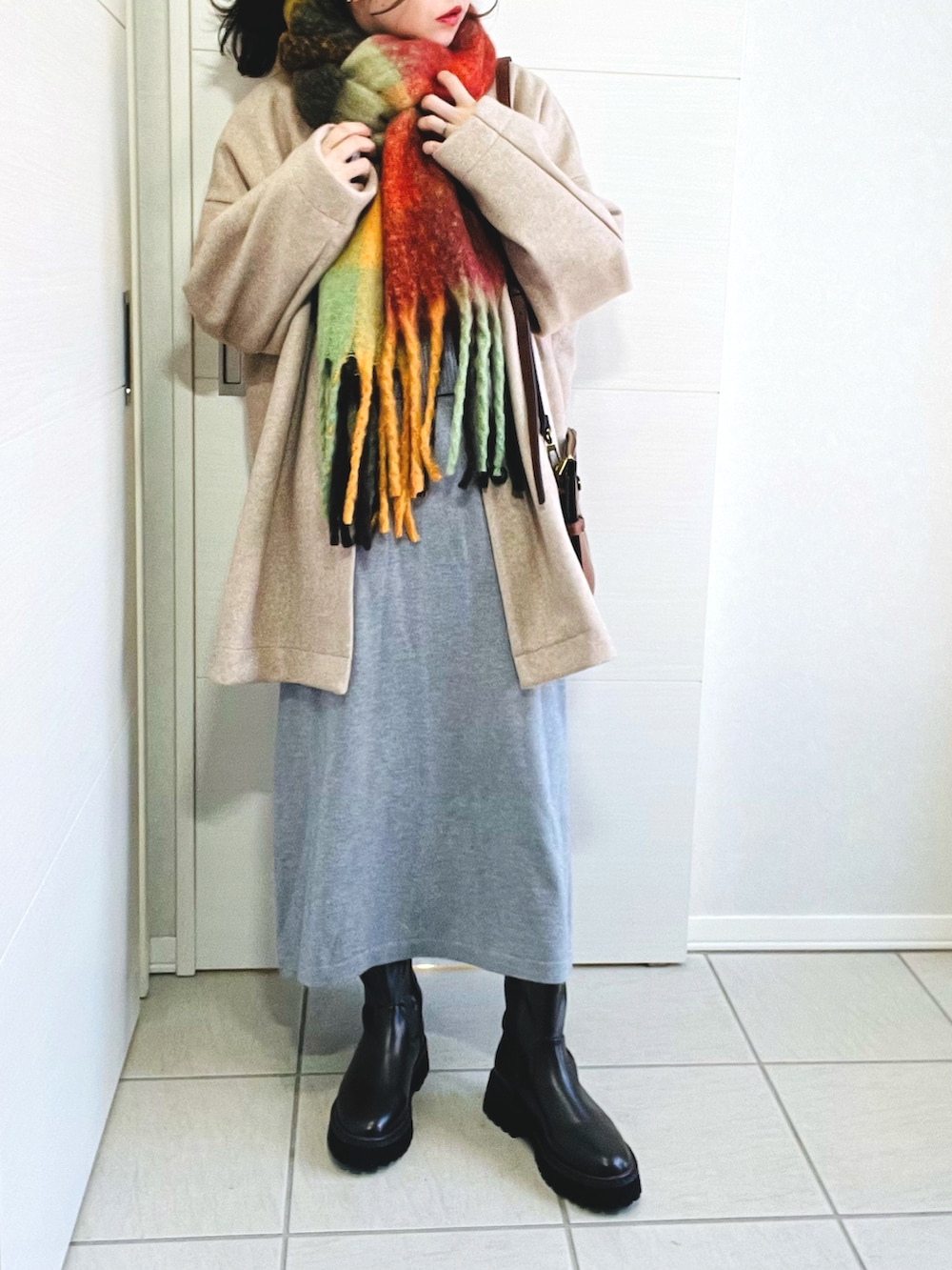 グレー系のワンピース、ピンク系のノーカラーコート、ブラウン系のブーツを着用したレディースの冬コーディネートの5枚目の写真