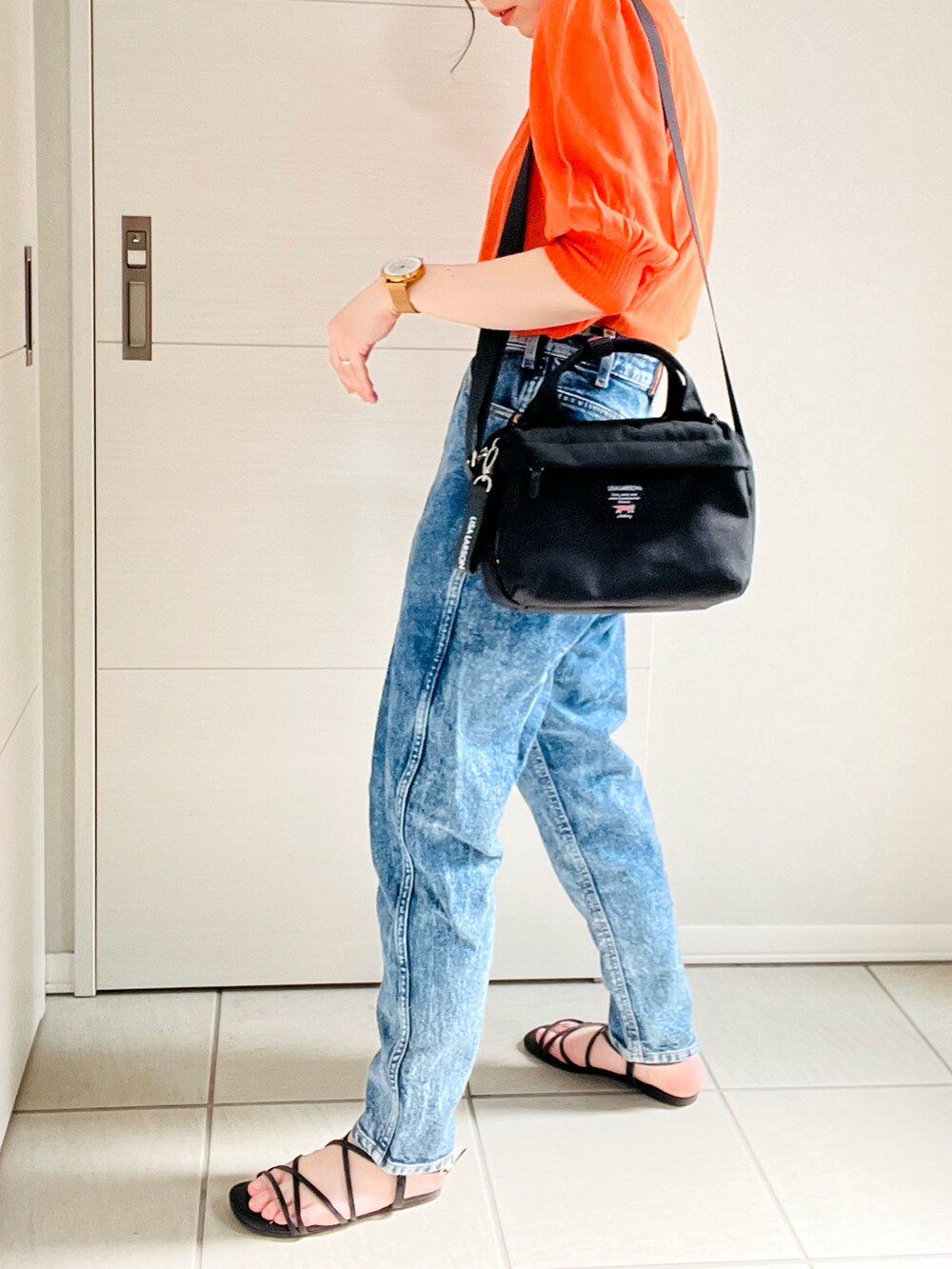 オレンジ系のニット/セーター、ブルー系のデニムパンツ、ブラック系のサンダルを着用したレディースの夏コーディネートの2枚目の写真