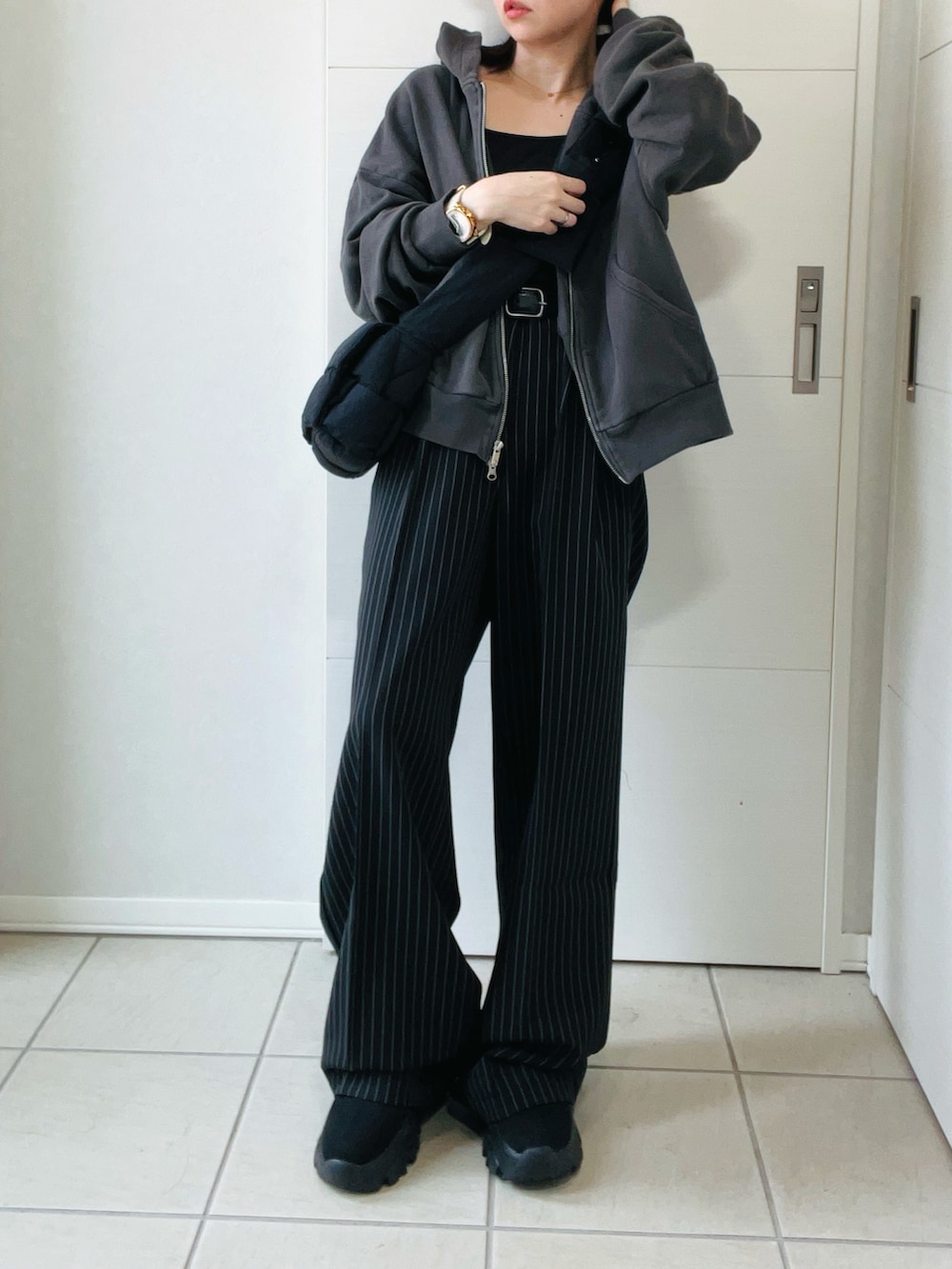 ブラック系のデニムパンツ、グレー系のパーカー、ブラック系のブーツを着用したレディースの秋コーディネートの4枚目の写真