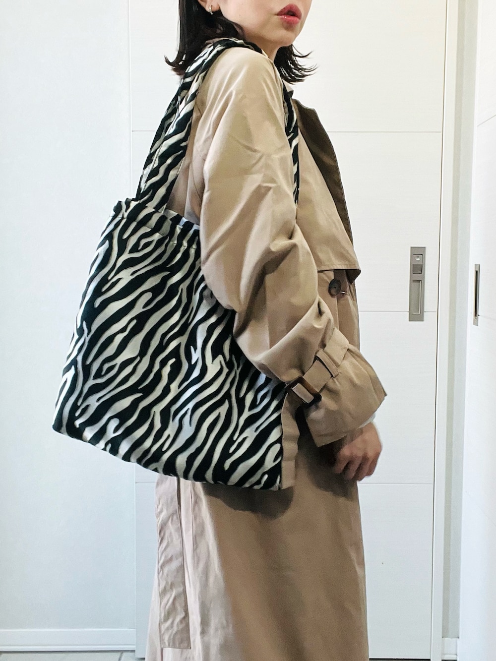 ベージュ系のトレンチコート、ホワイト系のニット/セーター、ブルー系のデニムパンツを着用したレディースの春コーディネートの3枚目の写真