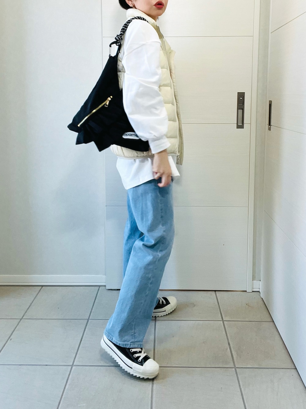 ホワイト系のダウンベスト、ホワイト系のTシャツ/カットソー、ブルー系のデニムパンツを着用したレディースの秋コーディネートの5枚目の写真