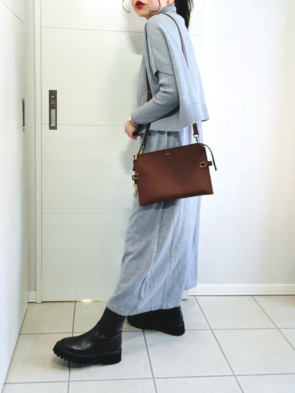 グレー系のワンピース、ピンク系のノーカラーコート、ブラウン系のブーツを着用したレディースの冬コーディネートの4枚目の写真