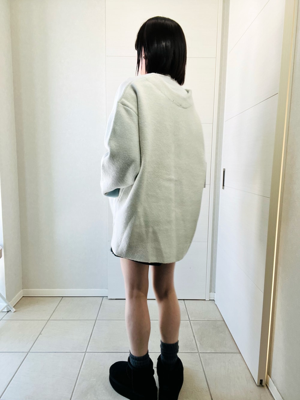 ホワイト系のカーディガン/ボレロ、ブラック系のブーツ、ブラック系のその他パンツを着用したレディースの冬コーディネートの3枚目の写真