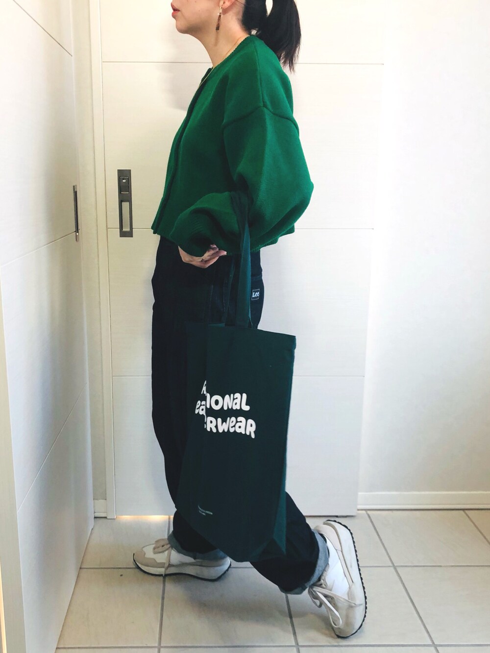 ブラック系のノーカラーコート、グリーン系のカーディガン/ボレロ、ブルー系のセットアップを着用したレディースの冬コーディネートの4枚目の写真